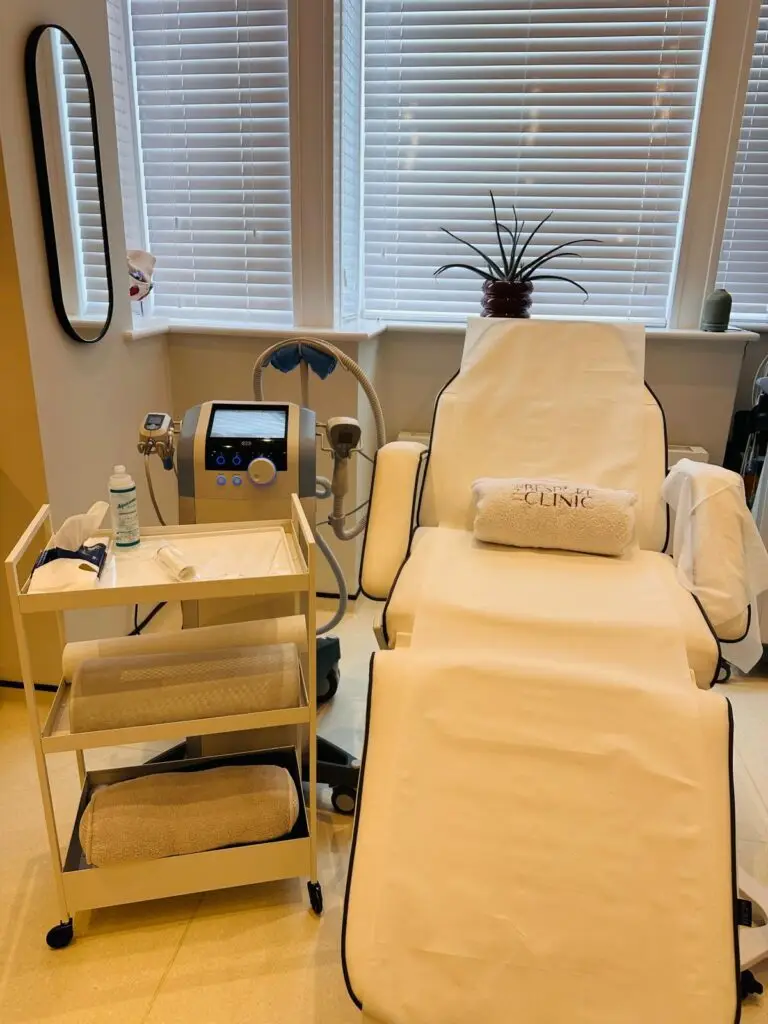 A treatment chair in a clinic with a mobile medical cart, hoses and a control screen nearby, ready for a procedure.